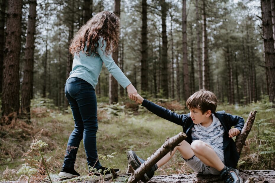 boy and girl playing on three tree log