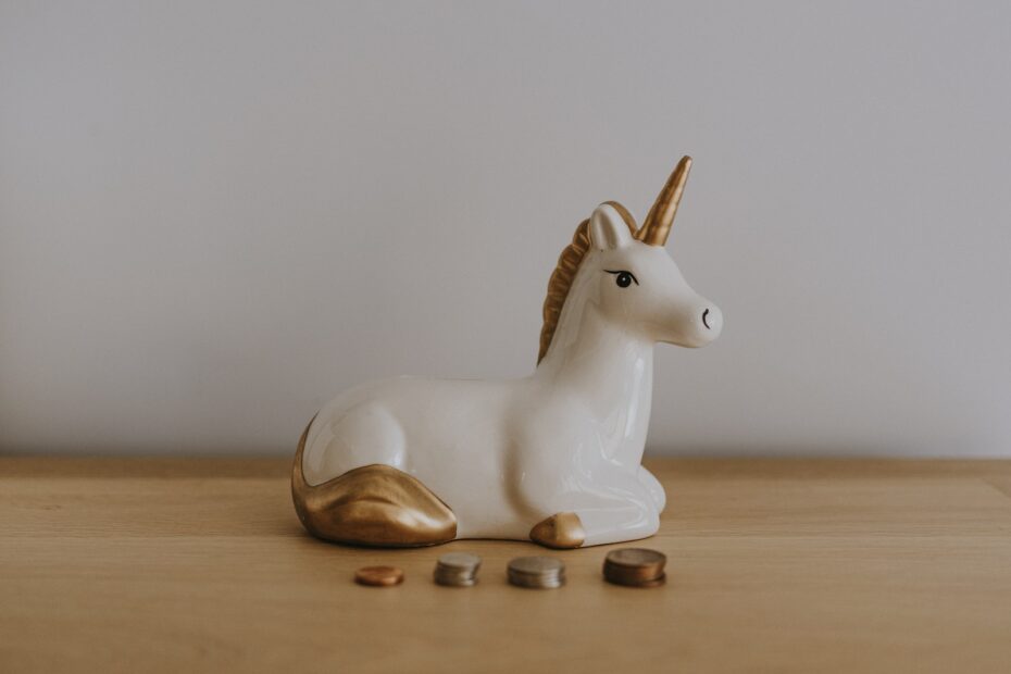 white and gold ceramic unicorn figurine near coins